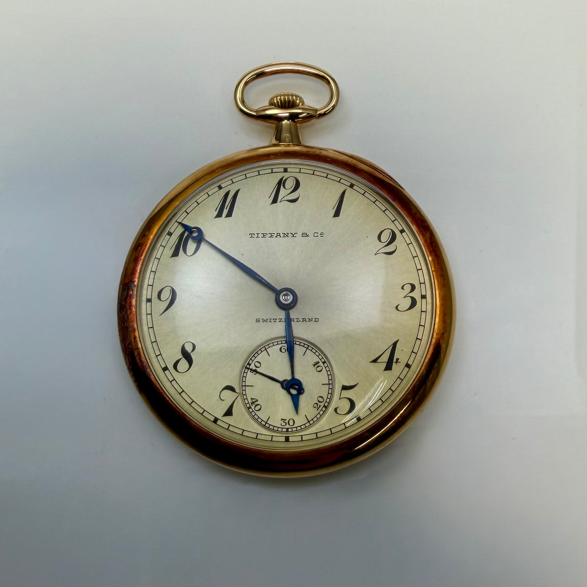 Tiffany and Co. pocket watch with a pale dial, blue hands, and a small seconds subdial.